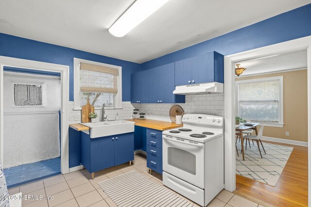 3712 Trask St, Jacksonville, FL 32205 - kitchen with white electric stove, blue cabinetry, under cabinet range hood, a sink, and backsplash