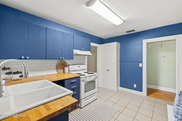 3712 Trask St, Jacksonville, FL 32205 - kitchen with electric stove, under cabinet range hood, butcher block countertops, blue cabinetry, and a sink