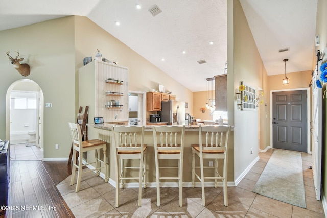 3684 Arava Dr, Green Cove Springs, FL 32043 - kitchen featuring stainless steel refrigerator with ice dispenser, high vaulted ceiling, arched walkways, plenty of natural light, and a peninsula