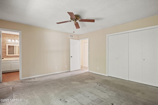 695 A1A N Unit 123, Ponte Vedra Beach, FL 32082 - unfurnished bedroom featuring carpet floors, a closet, ensuite bathroom, baseboards, and a textured ceiling