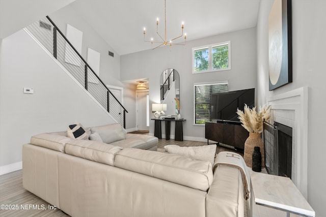338 Magnolia St, Atlantic Beach, FL 32233 - living room featuring high vaulted ceiling, a chandelier, stairway, light wood-style flooring, and baseboards