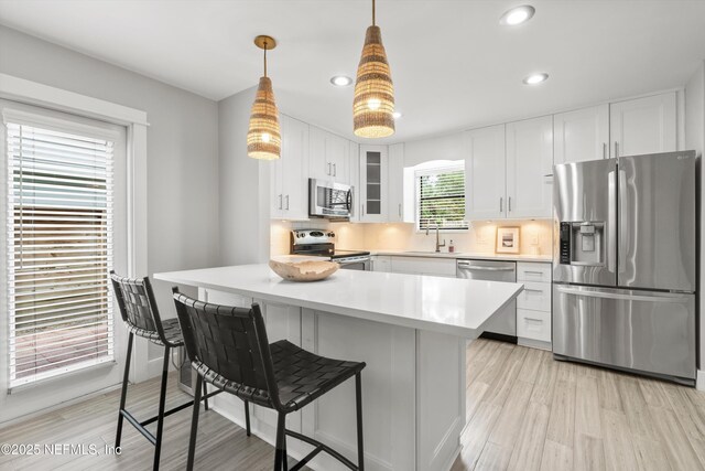 338 Magnolia St, Atlantic Beach, FL 32233 - kitchen with appliances with stainless steel finishes, glass insert cabinets, a kitchen bar, light countertops, and light wood-style flooring