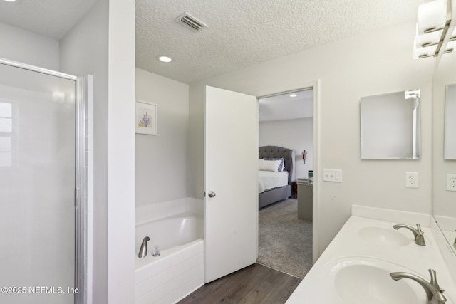864 Collinswood Dr W, Jacksonville, FL 32225 - full bathroom with wood finished floors, a shower stall, a garden tub, ensuite bathroom, and a textured ceiling