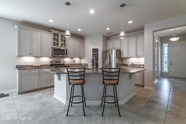 497 Convex Ln, Saint Augustine, FL 32095 - kitchen featuring stainless steel appliances, a breakfast bar area, a kitchen island with sink, dark stone countertops, and a textured ceiling