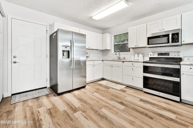 159 Twine St, Saint Augustine, FL 32084 - kitchen with appliances with stainless steel finishes, a textured ceiling, light countertops, and light wood-style flooring