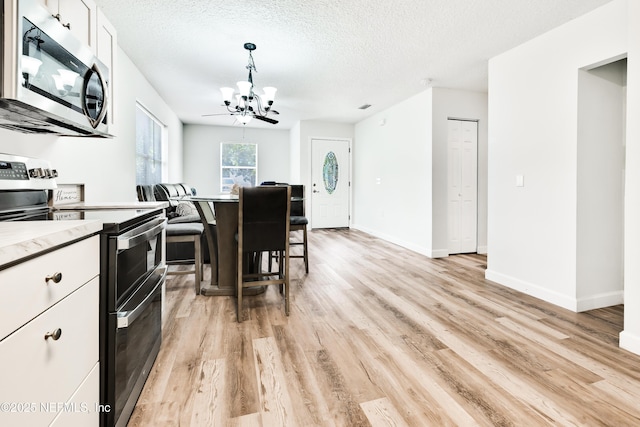 159 Twine St, Saint Augustine, FL 32084 - kitchen featuring appliances with stainless steel finishes, a chandelier, white cabinetry, light wood-style flooring, and baseboards