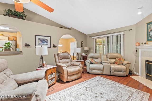 1275 Pirates Cove Ln, Fleming Island, FL 32003 - living room featuring arched walkways, lofted ceiling, wood finished floors, a premium fireplace, and a ceiling fan