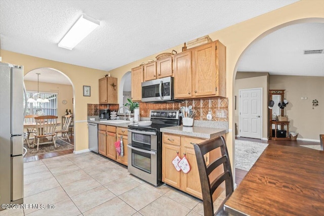 1275 Pirates Cove Ln, Fleming Island, FL 32003 - kitchen featuring appliances with stainless steel finishes, arched walkways, light countertops, a sink, and tasteful backsplash