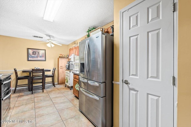 1275 Pirates Cove Ln, Fleming Island, FL 32003 - kitchen with appliances with stainless steel finishes, a textured ceiling, ceiling fan, brown cabinetry, and light tile patterned floors