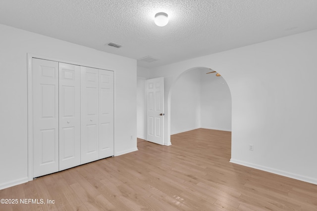 96428 Chester Rd, Yulee, FL 32097 - unfurnished bedroom with arched walkways, a textured ceiling, light wood-style floors, a closet, and baseboards
