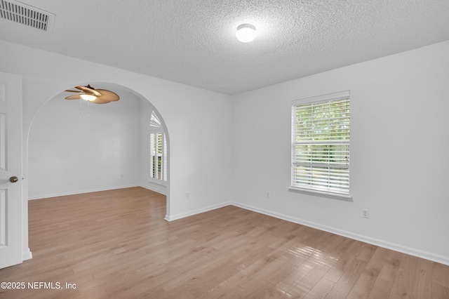 96428 Chester Rd, Yulee, FL 32097 - spare room with arched walkways, a textured ceiling, light wood-type flooring, a ceiling fan, and baseboards