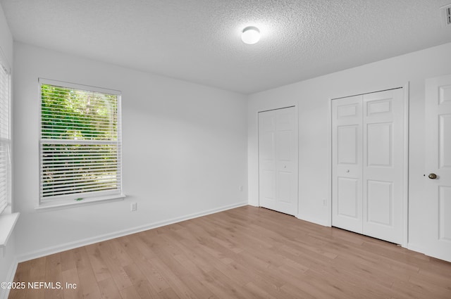 96428 Chester Rd, Yulee, FL 32097 - unfurnished bedroom featuring two closets, wood finished floors, a textured ceiling, and baseboards