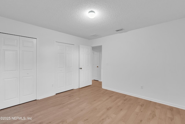 96428 Chester Rd, Yulee, FL 32097 - unfurnished bedroom featuring two closets, a textured ceiling, light wood-style flooring, and baseboards