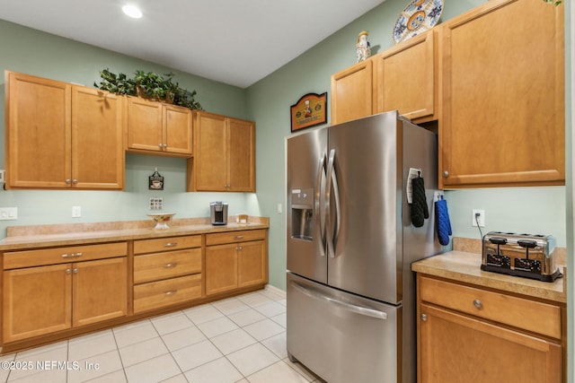 kitchen featuring stainless steel fridge, light countertops, and light tile patterned flooring