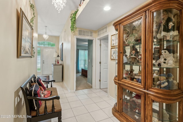hallway with a chandelier, light tile patterned floors, and baseboards
