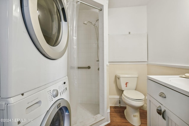 2143 Myra St, Jacksonville, FL 32204 - full bathroom with stacked washer and clothes dryer, a stall shower, toilet, wood finished floors, and a wainscoted wall