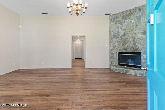 3060 Lewis Speedway, Saint Augustine, FL 32084 - unfurnished living room with a chandelier, wood finished floors, baseboards, and a stone fireplace
