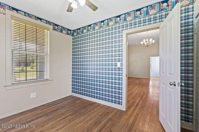 3060 Lewis Speedway, Saint Augustine, FL 32084 - unfurnished room with baseboards, wallpapered walls, a chandelier, wood finished floors, and a ceiling fan