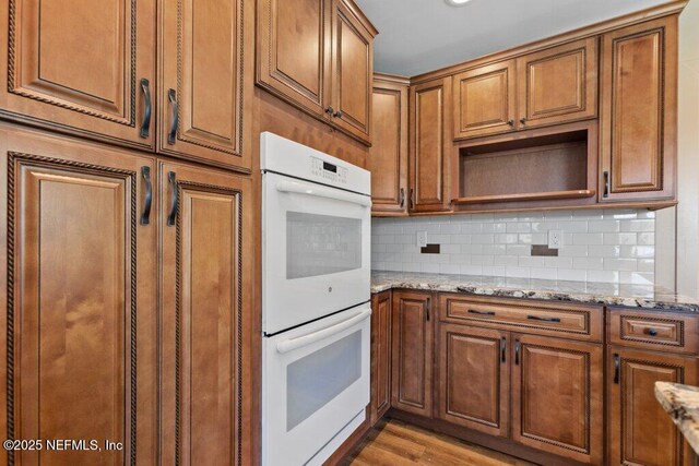 3060 Lewis Speedway, Saint Augustine, FL 32084 - kitchen featuring double oven, light stone countertops, open shelves, tasteful backsplash, and brown cabinets