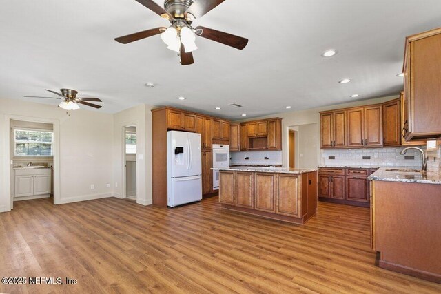 3060 Lewis Speedway, Saint Augustine, FL 32084 - kitchen with white appliances, a sink, a ceiling fan, a center island, and brown cabinetry