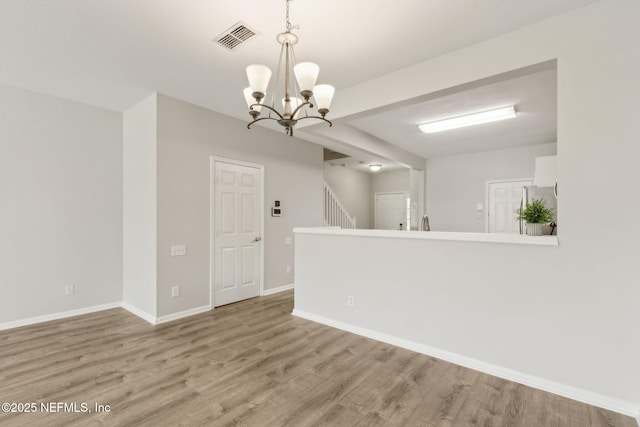 7990 Baymeadows Rd Unit 2404, Jacksonville, FL 32256 - spare room with a chandelier, light wood-style floors, baseboards, and stairway