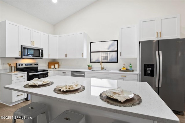 2767 Laten Ln, Jacksonville, FL 32216 - kitchen featuring appliances with stainless steel finishes, a sink, vaulted ceiling, a breakfast bar area, and light wood-style floors