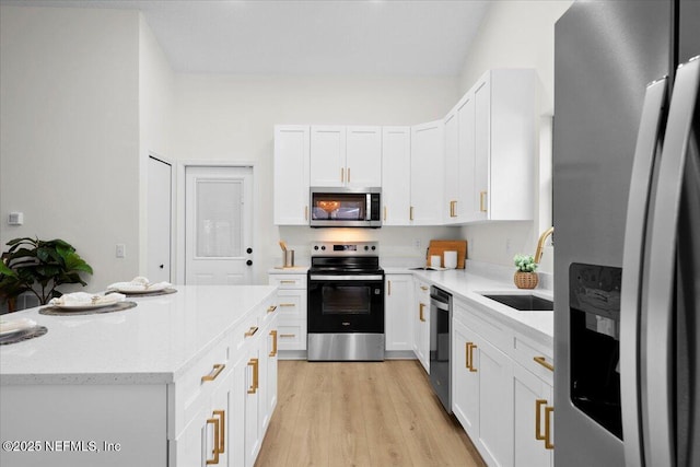2767 Laten Ln, Jacksonville, FL 32216 - kitchen featuring appliances with stainless steel finishes, white cabinets, light wood-style flooring, light stone counters, and a center island