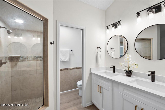2767 Laten Ln, Jacksonville, FL 32216 - full bathroom featuring toilet, a shower stall, double vanity, wood finished floors, and tile walls