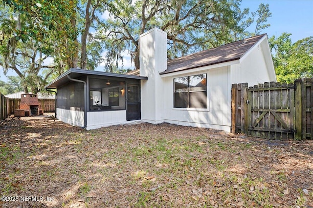 2767 Laten Ln, Jacksonville, FL 32216 - back of house featuring a sunroom, a chimney, a fenced backyard, and a gate