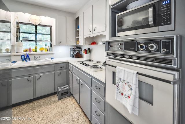 723 Montego Rd W, Jacksonville, FL 32216 - kitchen with white appliances, gray cabinetry, open shelves, a sink, and dark speckled floor