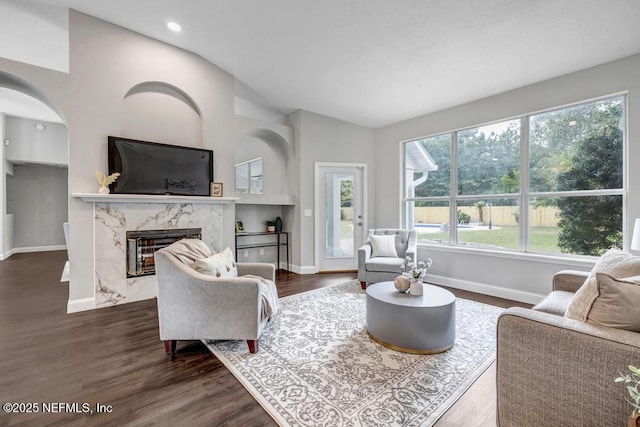 4833 Saddlehorn Trl, Middleburg, FL 32068 - living area featuring a high end fireplace, healthy amount of natural light, baseboards, vaulted ceiling, and arched walkways