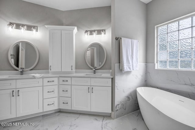 4833 Saddlehorn Trl, Middleburg, FL 32068 - full bathroom featuring marble finish floors, double vanity, a soaking tub, wainscoting, and tile walls