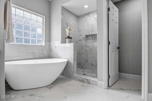 4833 Saddlehorn Trl, Middleburg, FL 32068 - bathroom with marble tiled flooring, a soaking tub, a marble finish shower, wainscoting, and tile walls