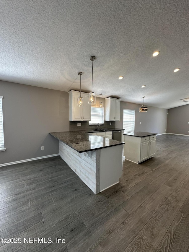 1456 Greenway Pl, Fleming Island, FL 32003 - kitchen with dark wood-type flooring, dark countertops, a peninsula, baseboards, and a textured ceiling