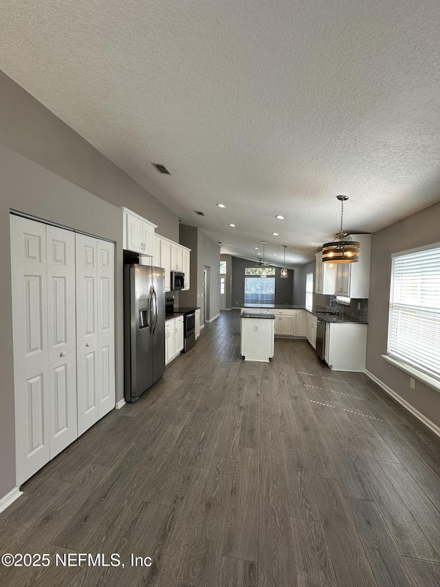 1456 Greenway Pl, Fleming Island, FL 32003 - kitchen with stainless steel appliances, dark wood finished floors, white cabinetry, a peninsula, and a textured ceiling