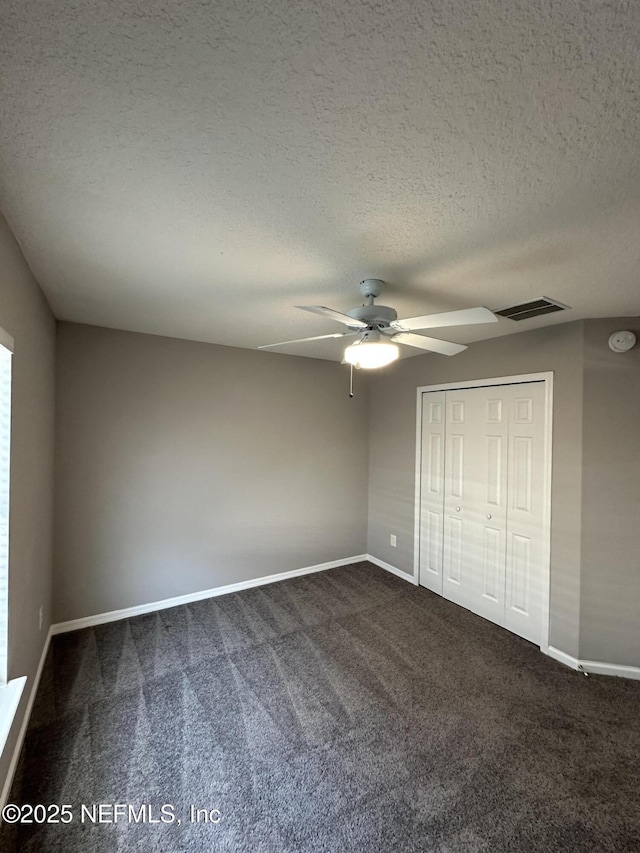 1456 Greenway Pl, Fleming Island, FL 32003 - unfurnished bedroom featuring dark colored carpet, a textured ceiling, baseboards, a closet, and ceiling fan