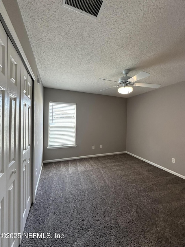 1456 Greenway Pl, Fleming Island, FL 32003 - unfurnished bedroom featuring dark carpet, baseboards, a textured ceiling, and a ceiling fan