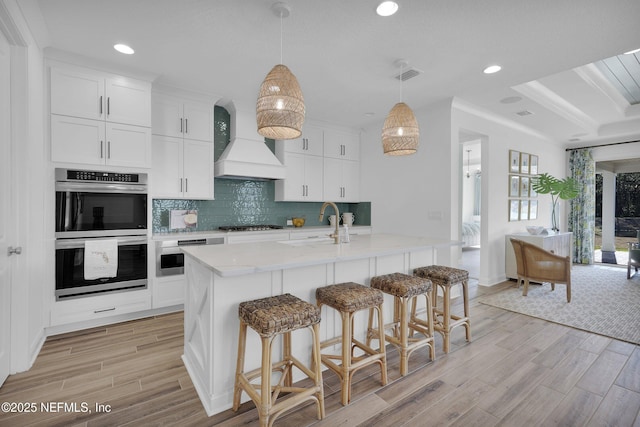 44 Sea Grn Way, Ponte Vedra, FL 32081 - kitchen with custom exhaust hood, double oven, light wood finished floors, a sink, and recessed lighting