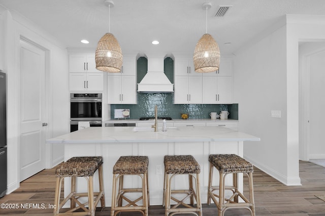 44 Sea Grn Way, Ponte Vedra, FL 32081 - kitchen with custom range hood, wood finished floors, stainless steel appliances, backsplash, and recessed lighting