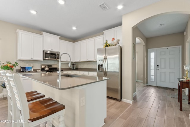 267 Ash Breeze Cv, Saint Augustine, FL 32095 - kitchen featuring appliances with stainless steel finishes, arched walkways, a sink, tasteful backsplash, and white cabinetry