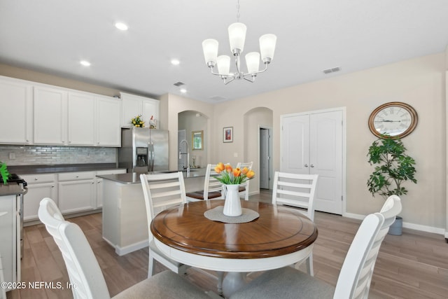267 Ash Breeze Cv, Saint Augustine, FL 32095 - dining room featuring arched walkways, light wood-style floors, a chandelier, recessed lighting, and baseboards