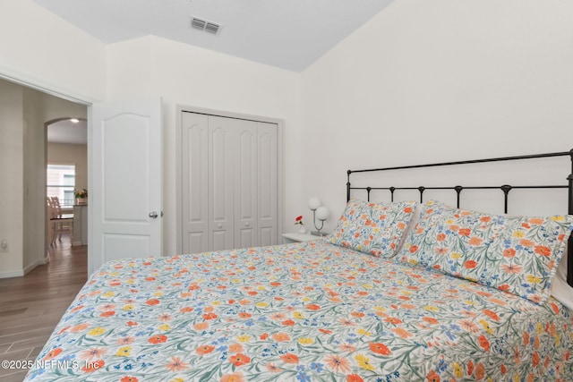 267 Ash Breeze Cv, Saint Augustine, FL 32095 - bedroom featuring arched walkways, wood finished floors, a closet, high vaulted ceiling, and baseboards