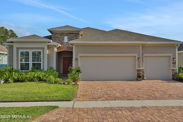 84754 Fall River Pkwy, Fernandina Beach, FL 32034 - view of front of home with decorative driveway, a garage, stone siding, a front lawn, and a shingled roof