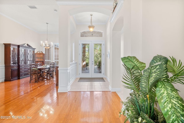 1460 Atlantic Breeze Way, Ponte Vedra Beach, FL 32082 - foyer entrance with arched walkways, a chandelier, light wood-style flooring, french doors, and crown molding
