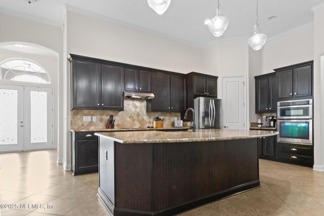 1098 Spanish Bay Ct, Orange Park, FL 32065 - kitchen with stainless steel appliances, under cabinet range hood, light tile patterned flooring, light stone countertops, and crown molding