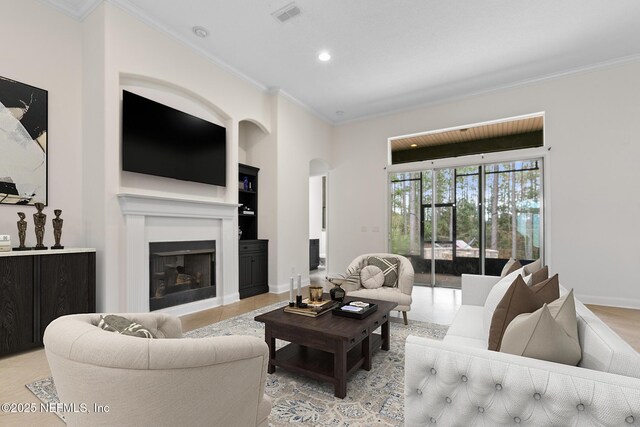 1098 Spanish Bay Ct, Orange Park, FL 32065 - living area with crown molding, arched walkways, a glass covered fireplace, recessed lighting, and built in shelves