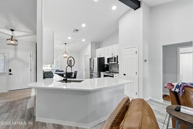 12489 Windy Willows Dr N, Jacksonville, FL 32225 - kitchen with appliances with stainless steel finishes, a sink, lofted ceiling, white cabinets, and tasteful backsplash
