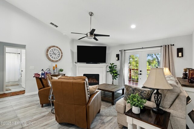 12489 Windy Willows Dr N, Jacksonville, FL 32225 - living area with a ceiling fan, a glass covered fireplace, lofted ceiling, french doors, and light wood-style flooring