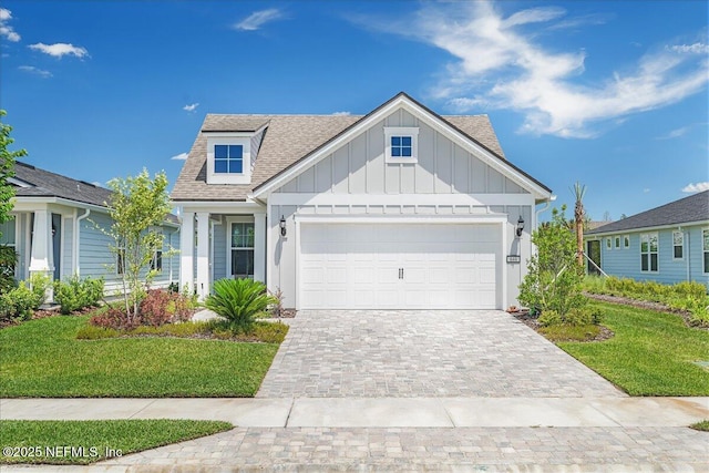 view of front facade with board and batten siding, an attached garage, a shingled roof, a front lawn, and decorative driveway
