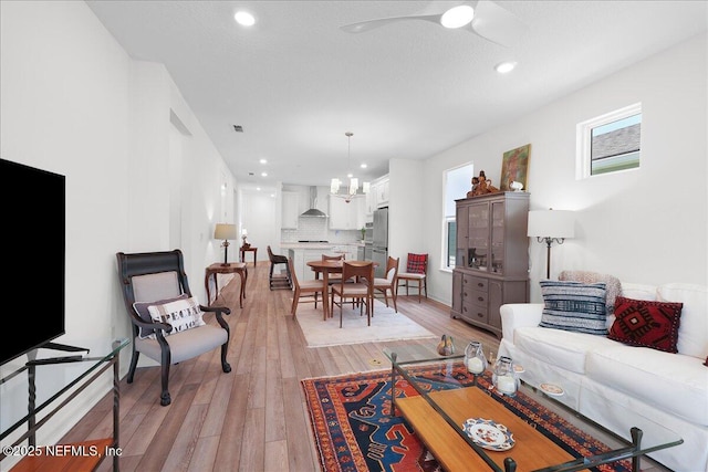 living room with light wood-style floors, a ceiling fan, and recessed lighting